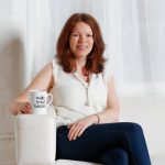 Smiling business woman in a branding portrait wearing a white top and jeans holding a cup