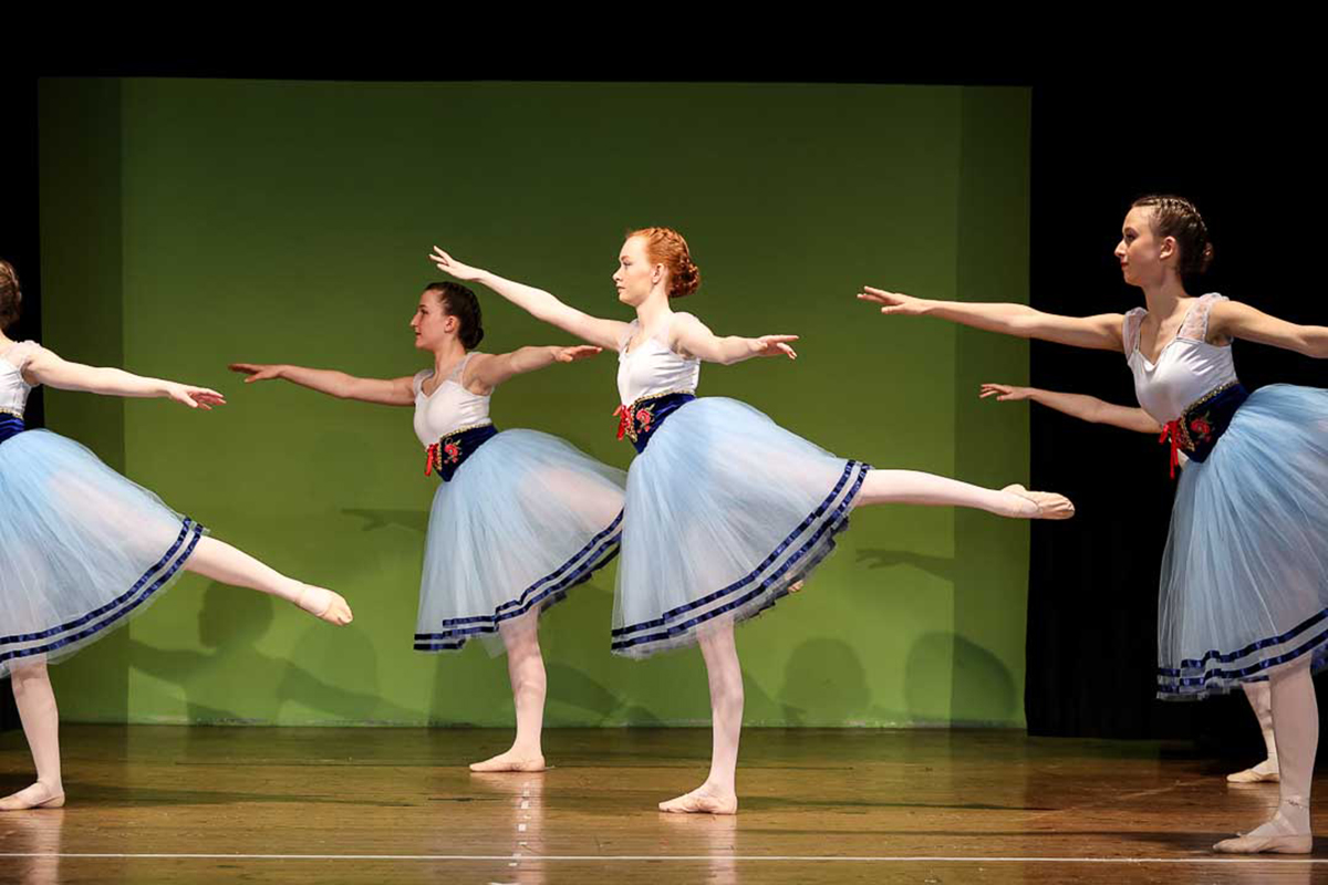 Ballet dancers wearing blue skirts with a white top