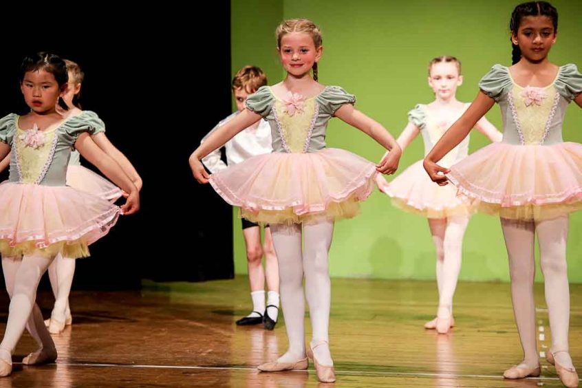 Ballet dancers wearing green and pink tutus and ballet shoes